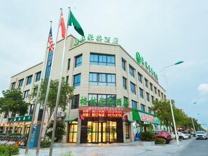 A hotel with multiple floors, a green signboard, and flags. - Greentree Inn Haining Chang an University Town (Jiaxing)