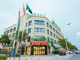 Un hotel con varios pisos, un letrero verde y banderas.