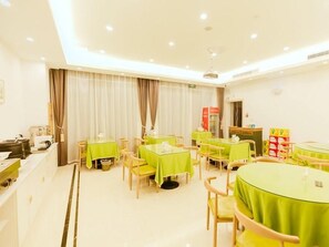 A hotel dining area with tables and chairs, a kitchen area, and a reception desk. - Greentree Inn Haining Chang an University Town (Jiaxing)