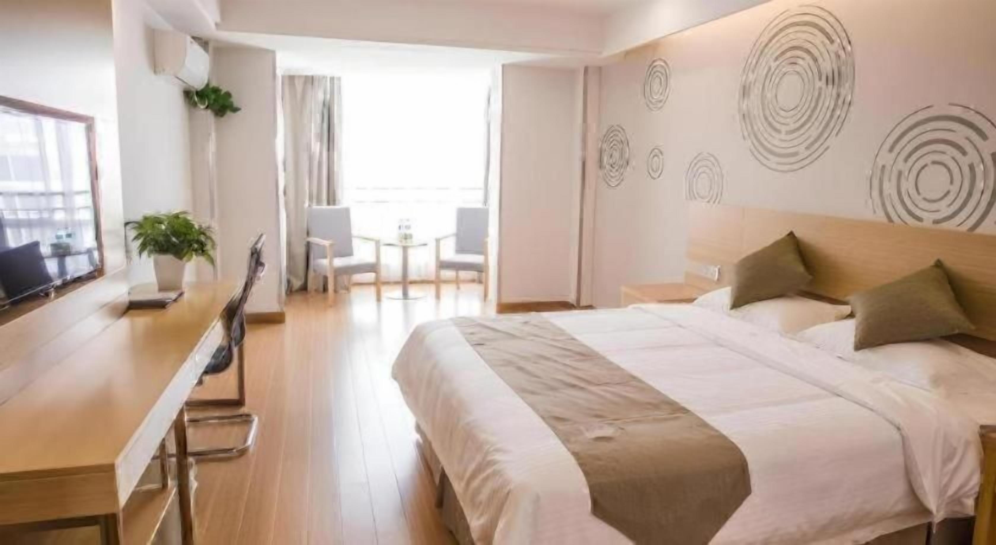 A hotel room with a bed, a desk, and a balcony.