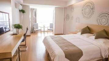 A hotel room with a bed, a desk, and a balcony.