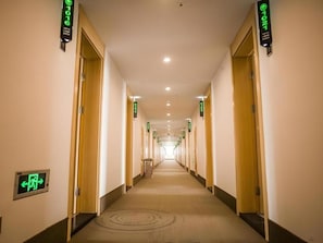 A hotel corridor with doors on both sides, overhead directional signs, and a carpeted floor. - Greentree Inn Suqian Suyu District Red Star Macall (Suqian)