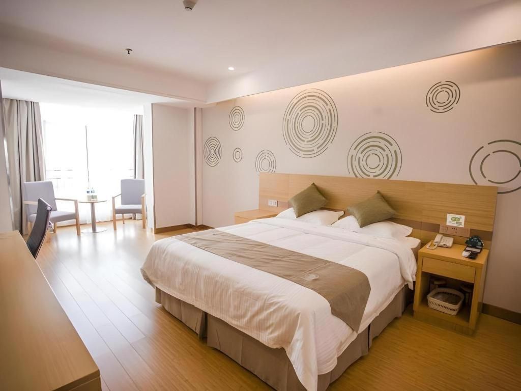 A hotel room with a bed, bedside table, and a desk.
