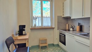Eine kleine Küche mit Fenster, einer Kaffeemaschine, einem Spülbecken und einem Herd.