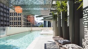 Une piscine intérieure dotée de chaises longues et d’une structure en forme de pergola.