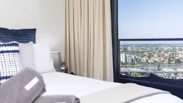 A hotel room with a bed, a view of a cityscape through a large window, and a curtain.