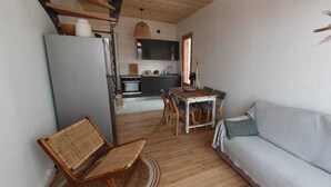 Een knus woongedeelte met een kitchenette, een eethoek en een slaapbank.