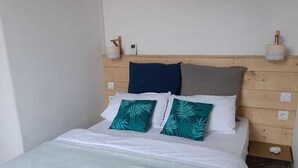 Een slaapkamer met een bed, houten hoofdbord, nachtkastjes en een hanglamp.