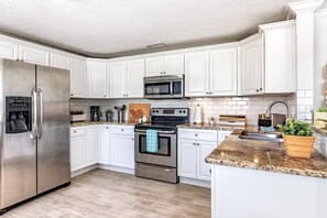 Natural solid stone countertops.  Cabinets filled with plenty of dishes and glasses for the whole group.