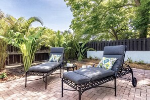 Relax in a serene outdoor space surrounded by lush greenery and comfortable lounge chairs.