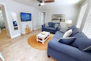 Un salon avec un canapé bleu, une table basse et un ventilateur de plafond.