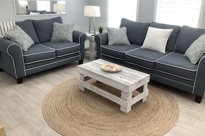 A living room with two dark sofas, a round coffee table, and a woven rug. - Perfect Location, Dog Friendly, Mins to Siesta Key (Sarasota)