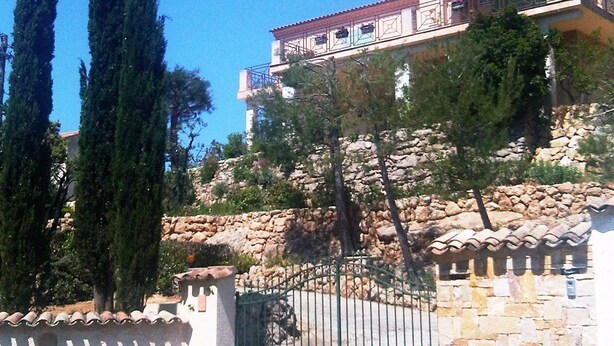 Un immeuble à plusieurs étages, doté d’une façade en pierre, d’un balcon et d’une entrée fermée par un portail.