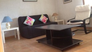 Un salon avec un canapé, un fauteuil, une petite table et une lampe.