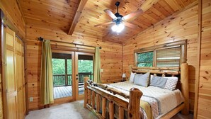 A wooden cabin bedroom with a bed, a ceiling fan, and a balcony. - Safe Haven- Mountain View-hot tub-wifi- pool table (Morganton)