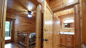 A wooden cabin interior with a bed, a bathroom, and a kitchen area. - Safe Haven- Mountain View-hot tub-wifi- pool table (Morganton)