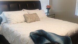 A neatly made bed with a white duvet, a dark headboard, and a blue blanket draped over the foot of the bed. - Cute, Clean & Comfortable in the Best Community! (Gilbert)