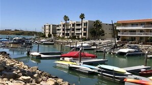 Marina com barcos atracados, um edifício com vários andares e um céu azul límpido.