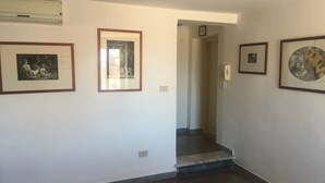 Un corridoio con opere d'arte incorniciate alle pareti, una scala e una sedia bianca in un angolo.