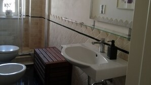 Un baño con inodoro, bidé y lavabo con espejo encima.