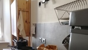 Una cocina con un lavamanos de acero inoxidable, una hogaza de pan, una tabla de cortar y una olla sobre la encimera.