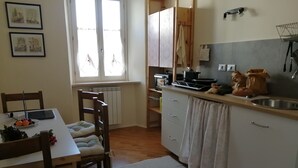 Una cocina con una mesa de comedor, sillas, un radiador, un fregadero y una ventana.