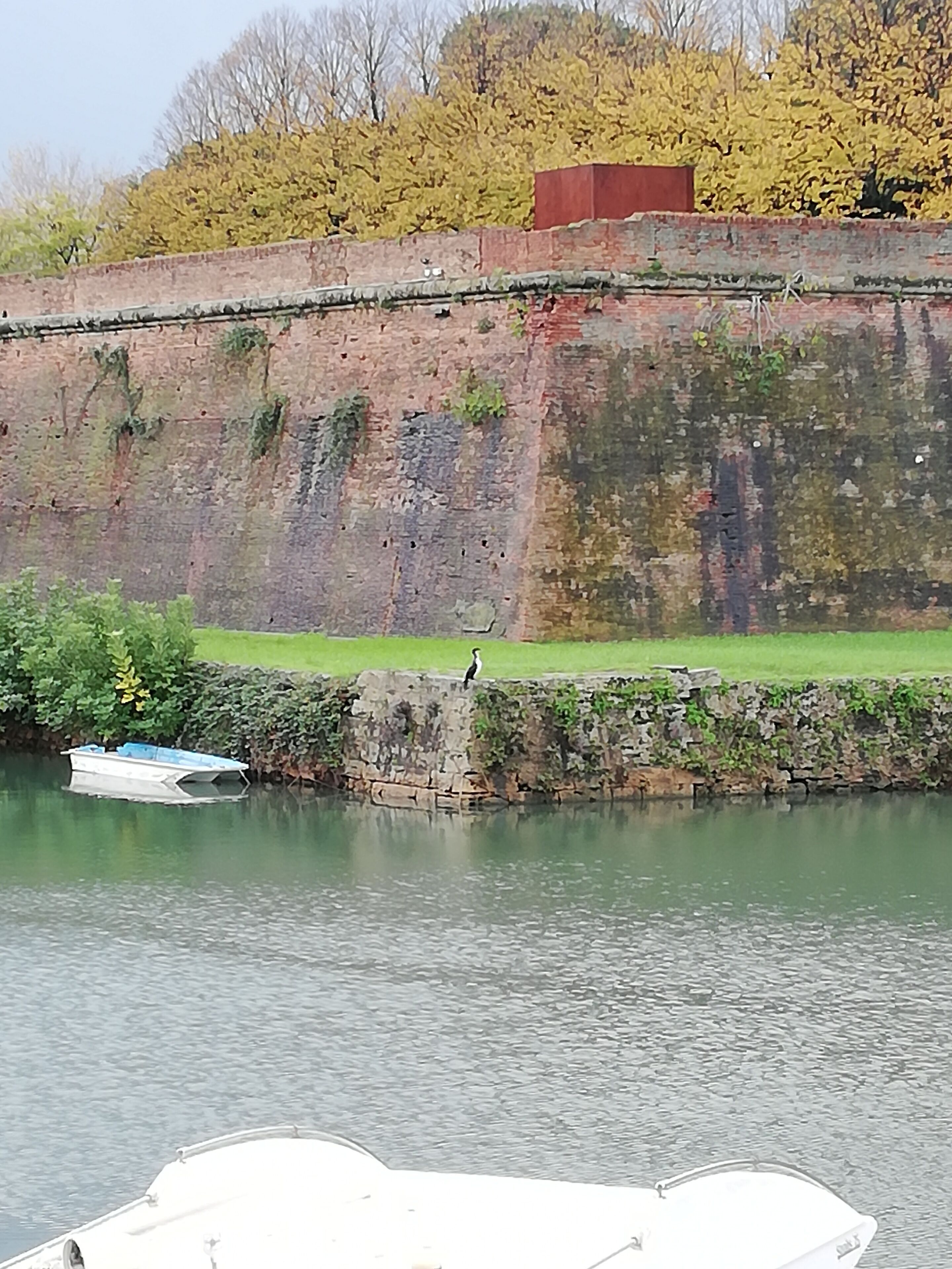 Ein Fluss mit einer Steinmauer und einem Boot, das an der linken Seite vertäut ist.