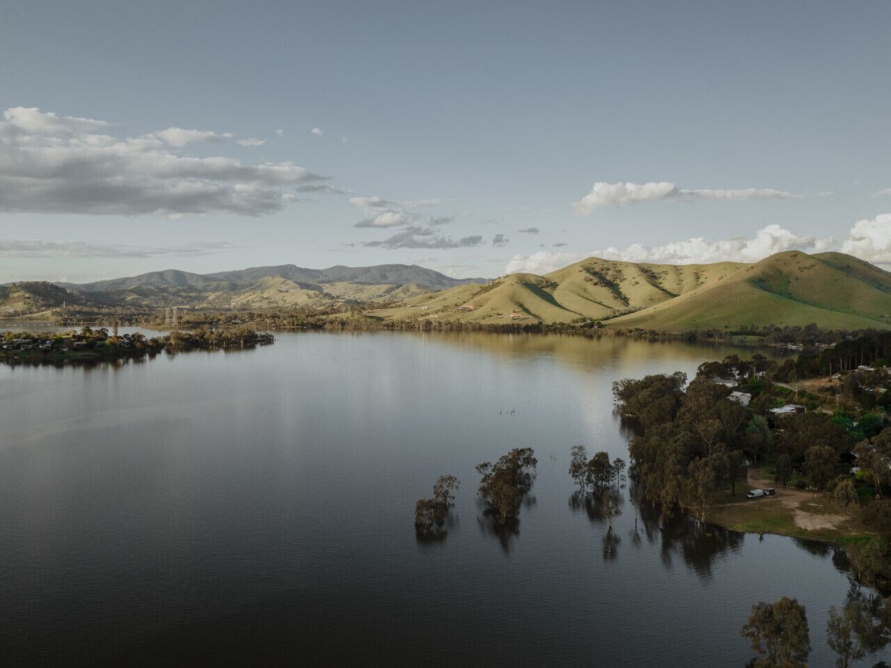 A lake with surrounding hills and a small settlement.