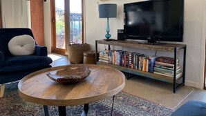 A living room with a sofa, a coffee table, a TV, a bookshelf, and a painting on the wall. - A perfect escape for couples & families & seniors (Bonnie Doon)