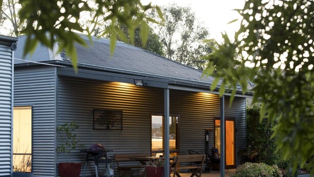 A metal building with a covered patio, outdoor seating, and potted plants. - A perfect escape for couples & families & seniors (Bonnie Doon)