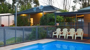 A swimming pool with a covered patio area, outdoor seating, and a fenced garden. - A perfect escape for couples & families & seniors (Bonnie Doon)