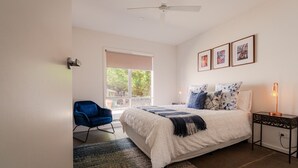 A bedroom with a bed, a chair, a nightstand, a lamp, and a window. - A perfect escape for couples & families & seniors (Bonnie Doon)