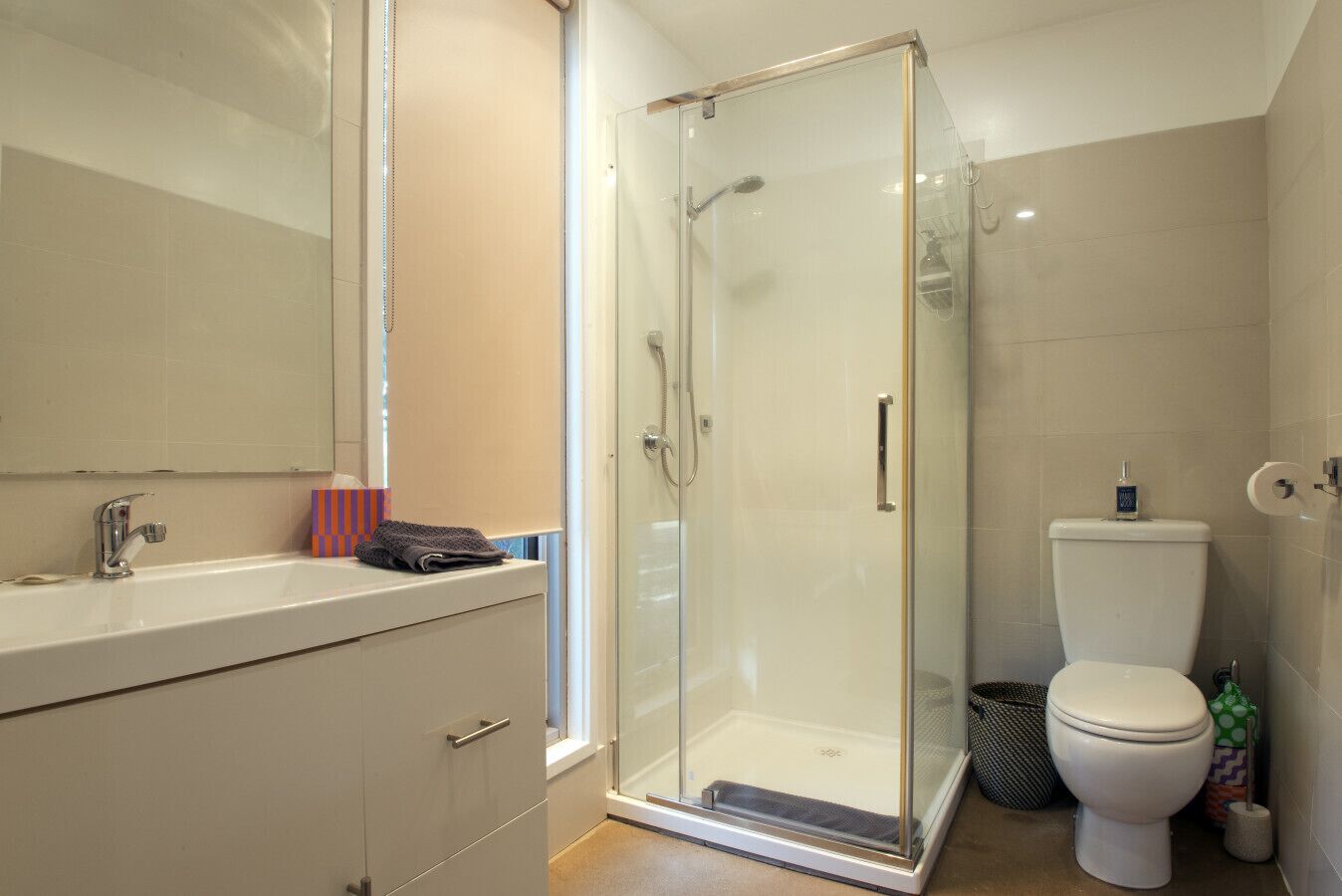 Un baño moderno con ducha envuelta en vidrio, un lavabo blanco y un inodoro.