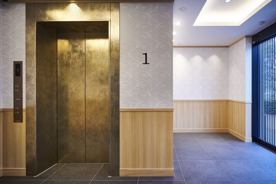 A modern elevator with a metallic finish, a wall-mounted number '1' sign, and a wooden panel design on the adjacent wall.