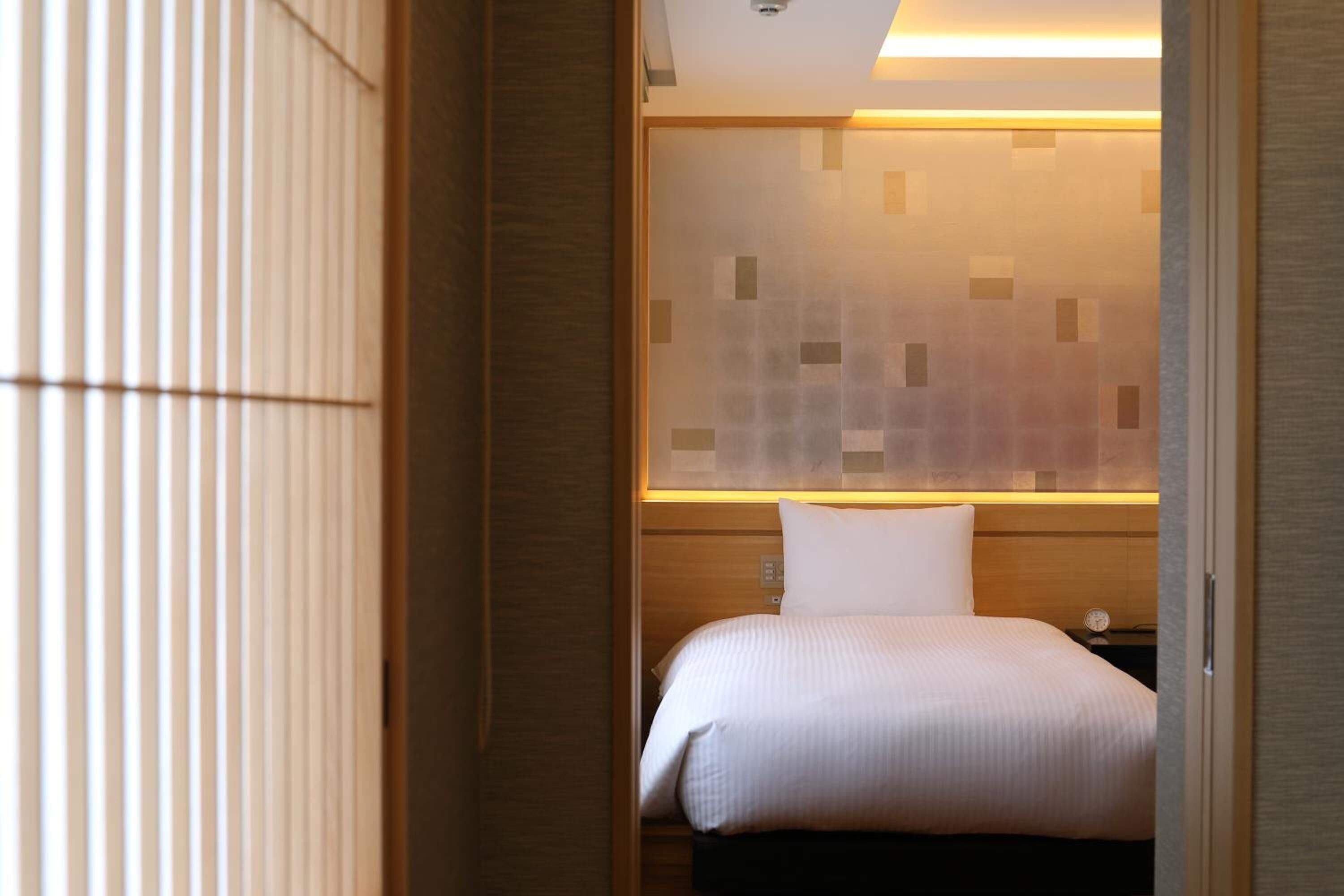 Una habitación de hotel con cama, mesita de noche y una pared con diseño geométrico.