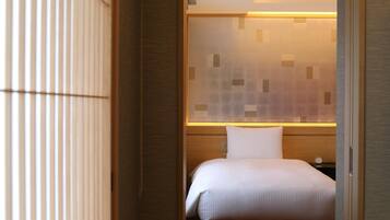 Una habitación de hotel con cama, mesita de noche y una pared con diseño geométrico.