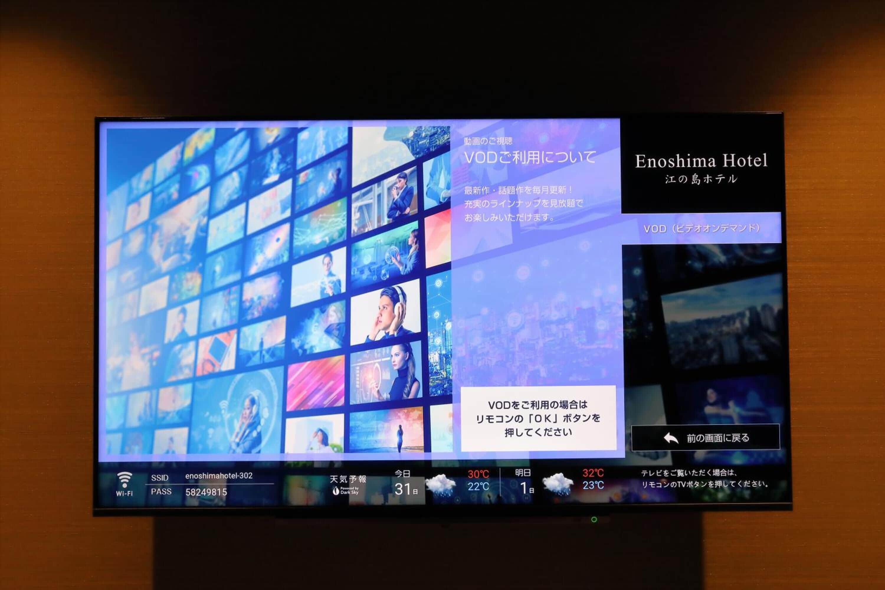 A television screen displaying a hotel interface with multiple room options, weather information, and a VOD service advertisement.