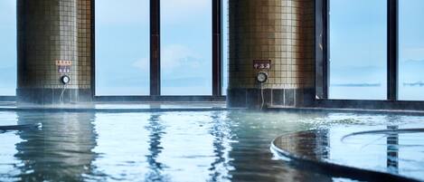 An indoor swimming pool with tiled walls and windows.