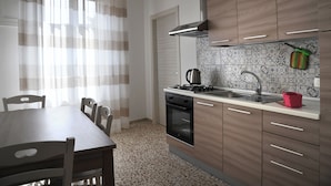 Eine moderne Küche mit Esstisch und Stühlen, einem Herd, Backofen und Spüle.