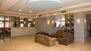 A spacious lobby with a high ceiling, seating area, and a stone wall. - Hotel Alexander the Great (Zakynthos)