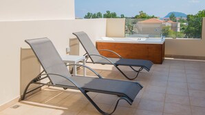 A terrace with two lounge chairs and a wooden table with a sink. - Hotel Alexander the Great (Zakynthos)
