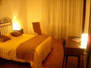 Una habitación de hotel con una cama, una silla, una mesa y una lámpara.