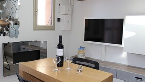Une cuisine moderne avec une table en bois, une bouteille de vin et des verres, un téléviseur et un miroir fixé au mur.
