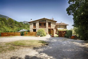 A stone house with a gravel driveway and a wooden fence.