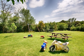 A grassy outdoor area with a picnic table, a swing set, and children's toys. - Mountain View | Stylish Apt | Luxury Bath | Forest (Sales De Llierca)