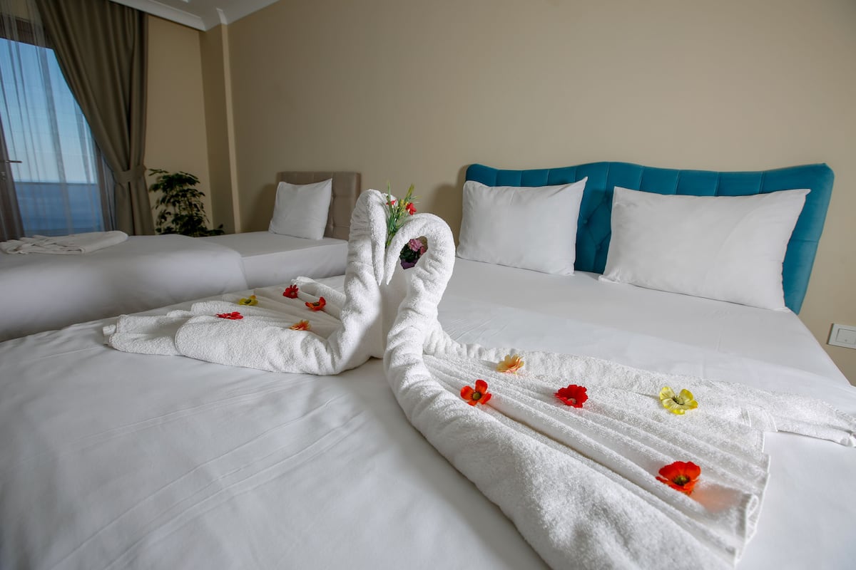 A hotel room with two beds, each with white linens and a blue headboard.