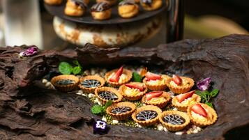 A variety of desserts on a rustic wooden surface, including tarts with strawberries and mint leaves.