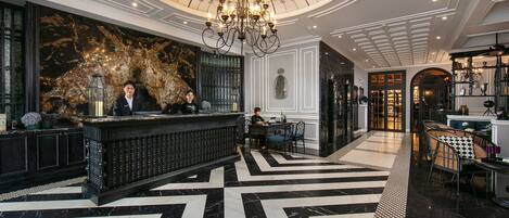 A lobby with a black and white marble floor, a reception desk, and a chandelier.