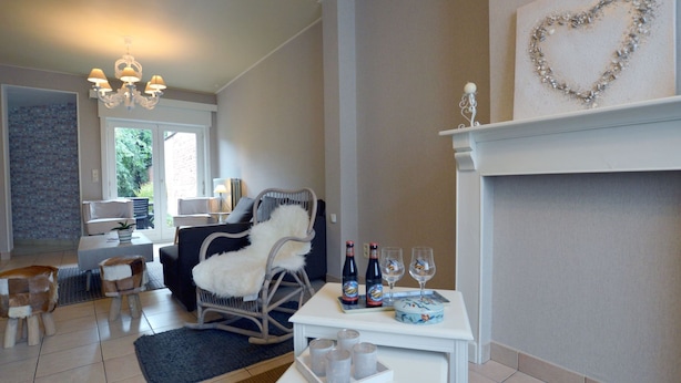 A living room with a fireplace, a chandelier, and a dining area with a table set for two. - West Flanders Vacation Home (Comines-Warneton)