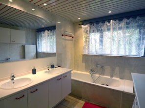 Une salle de bain moderne avec un double vasque, une baignoire et un grand miroir.